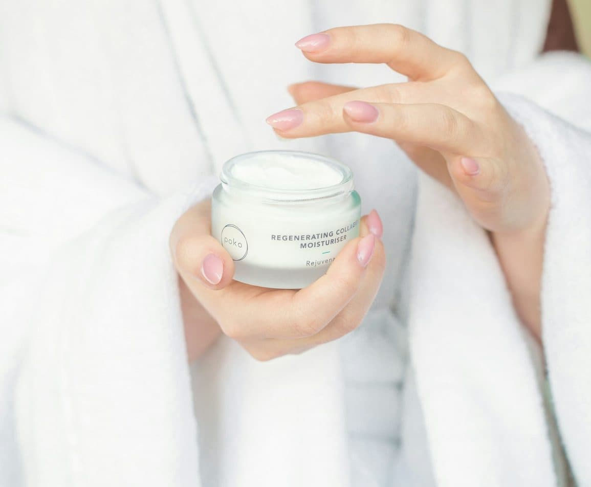 Hands holding an open jar of face cream