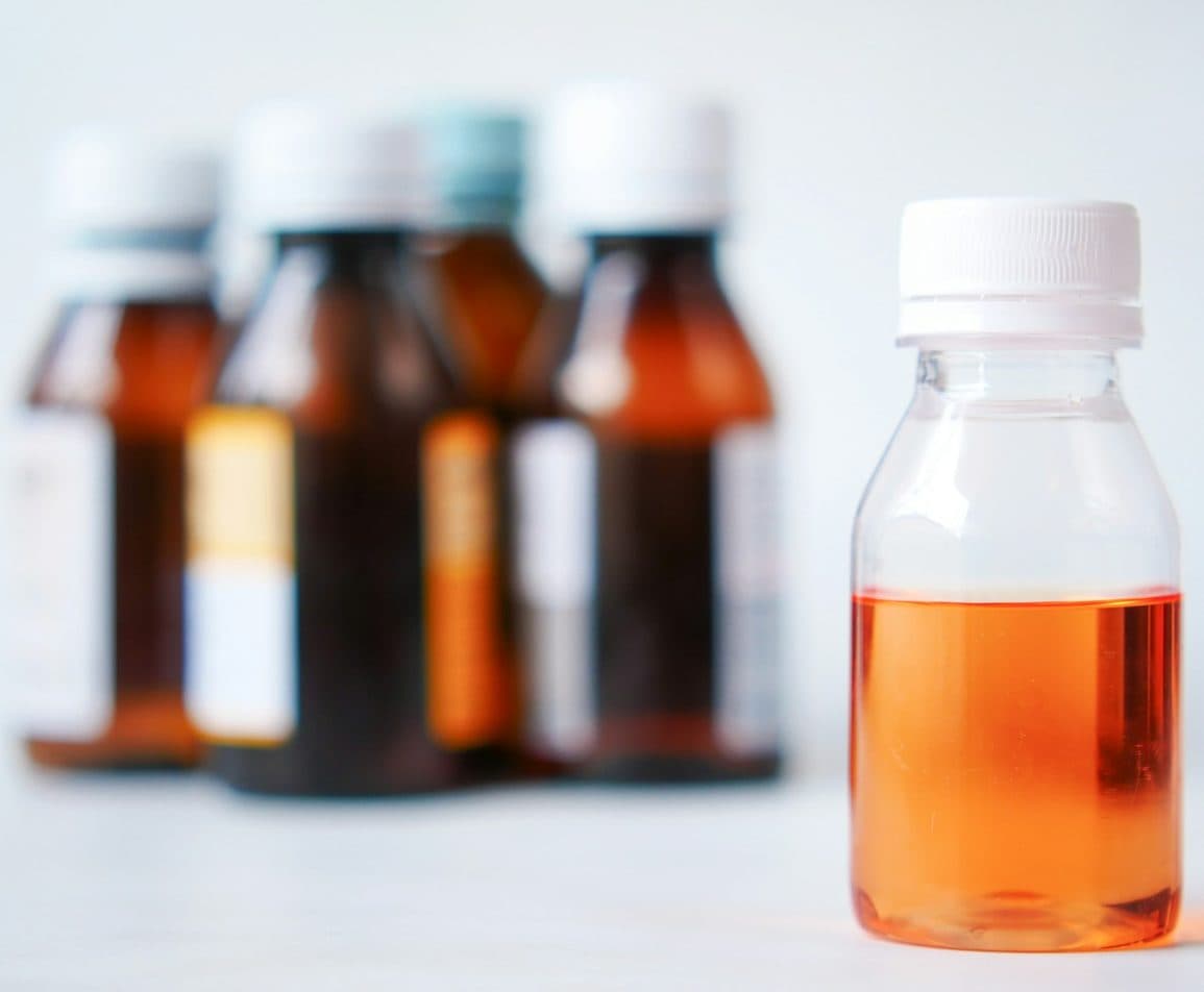 Amber medicine bottles beside a bottle of orange liquid